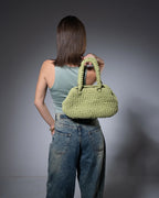 Person holding a green handbag against a gray background
