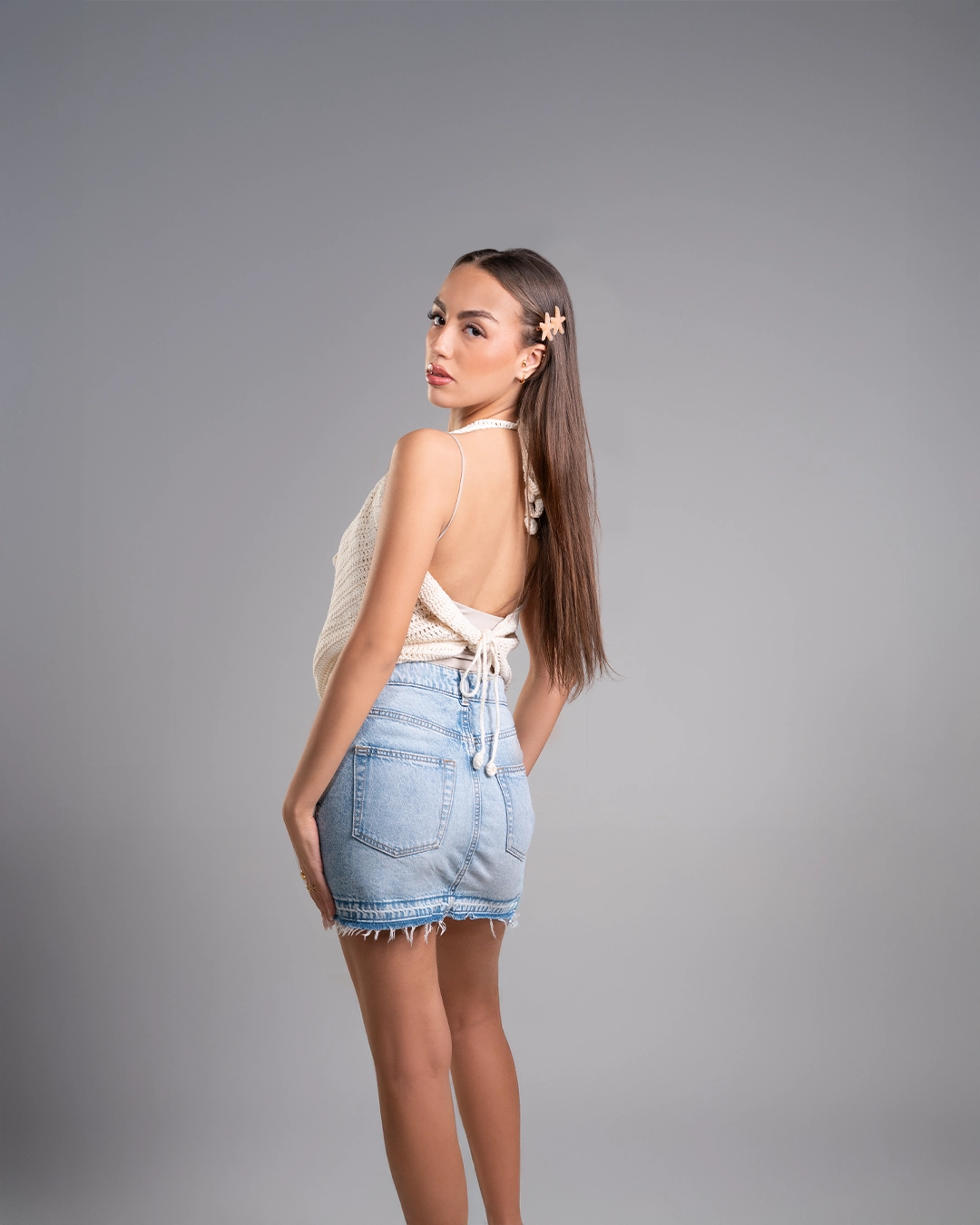 Woman wearing a white top and denim shorts on a gray background