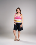 Woman wearing a colorful sleeveless top and black shorts on a gray background