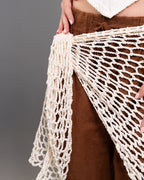 Brown skirt with a white lace shawl draped over it against a gray background