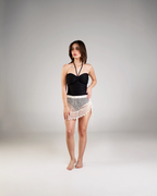 Woman wearing a black strapless top and white lace skirt on a gray background