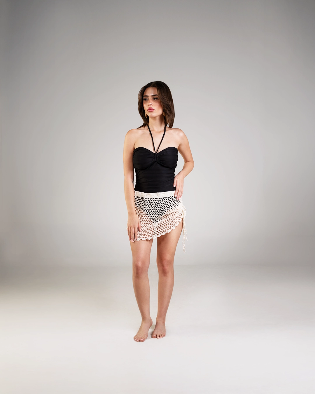 Woman wearing a black strapless top and white lace skirt on a gray background