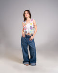 Woman wearing a colorful sleeveless top and blue jeans on a gray background