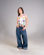 Woman wearing a colorful sleeveless top and blue jeans on a gray background