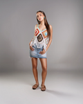 Woman wearing a colorful crochet top and denim shorts on a gray background