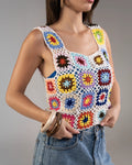 Woman wearing a colorful crochet tank top against a gray background