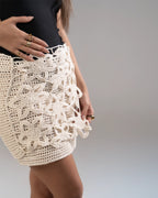 Person wearing a white crochet skirt on a plain background