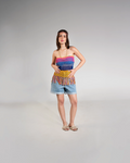 Woman wearing a colorful striped top and denim shorts on a gray background