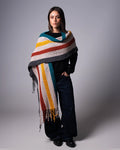 Woman wearing a colorful striped shawl against a gray background