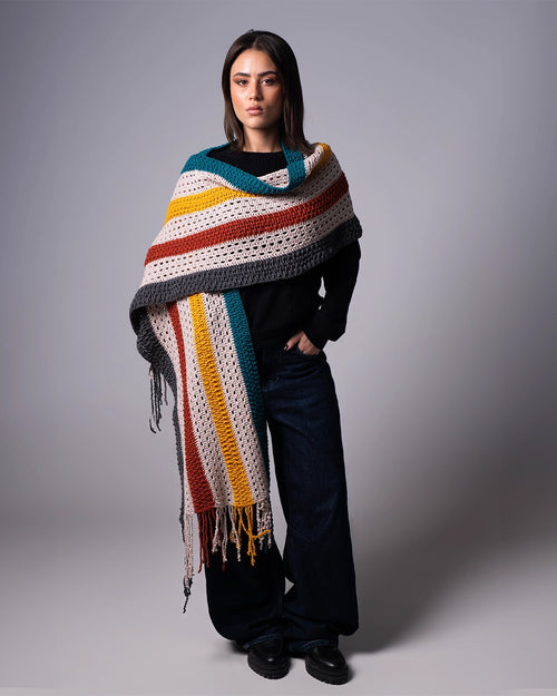Woman wearing a colorful striped shawl against a gray background