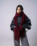 Person wearing a large burgundy scarf on a plain background
