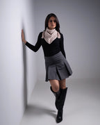 Woman wearing a black sweater, gray skirt, and knee-high boots against a white background