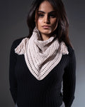 Woman wearing a beige knitted scarf against a dark background