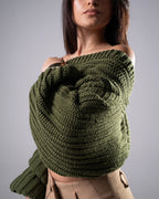 Woman wearing a green knitted sweater against a gray background