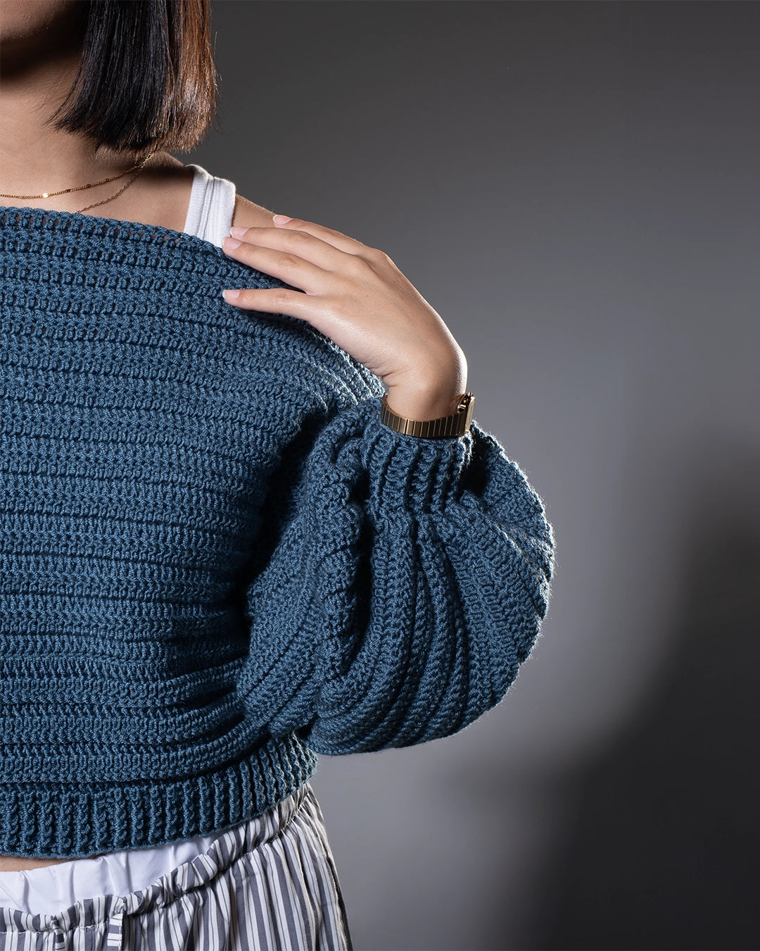 Person wearing a blue knitted sweater against a gray background