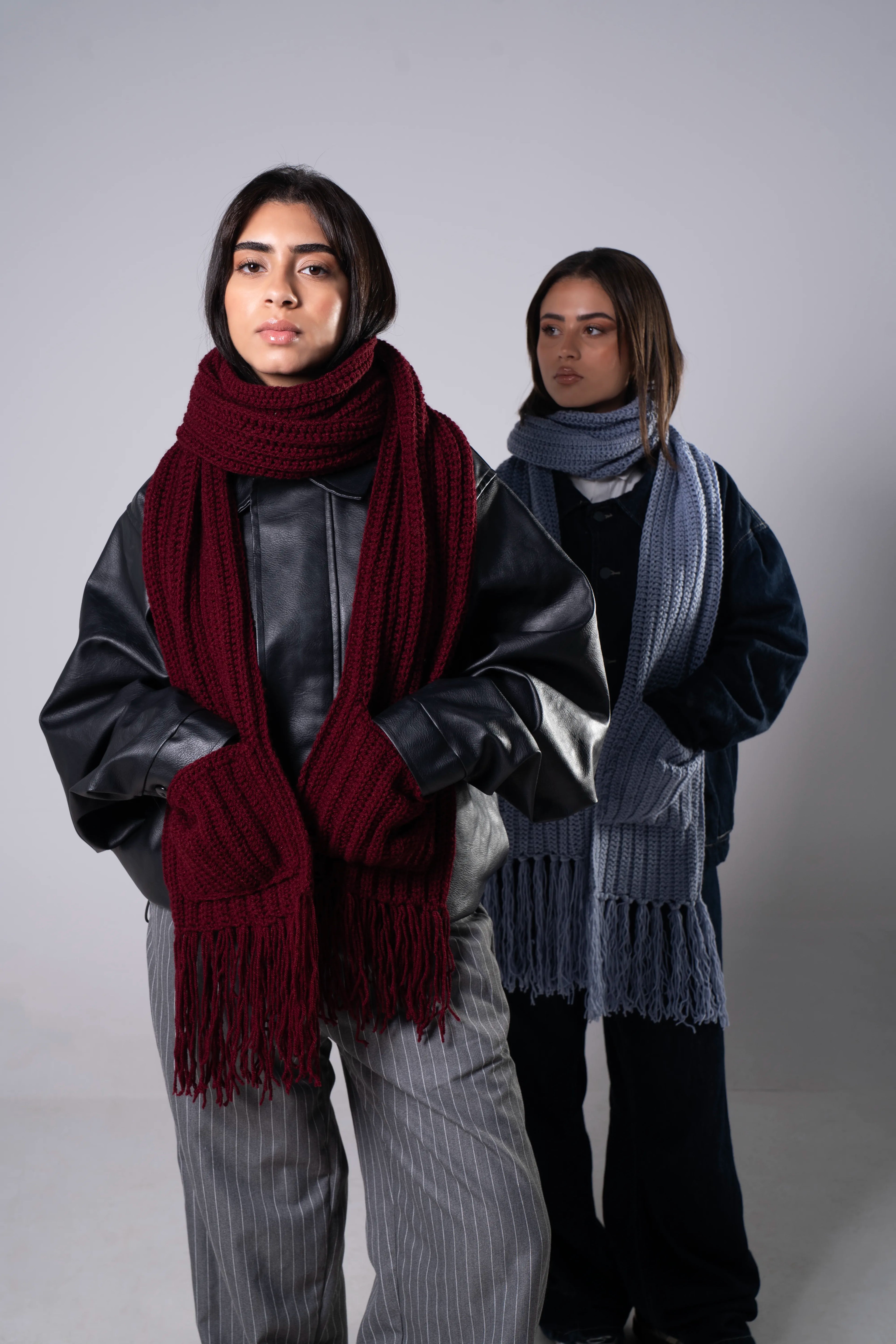 Two people wearing scarves against a plain background