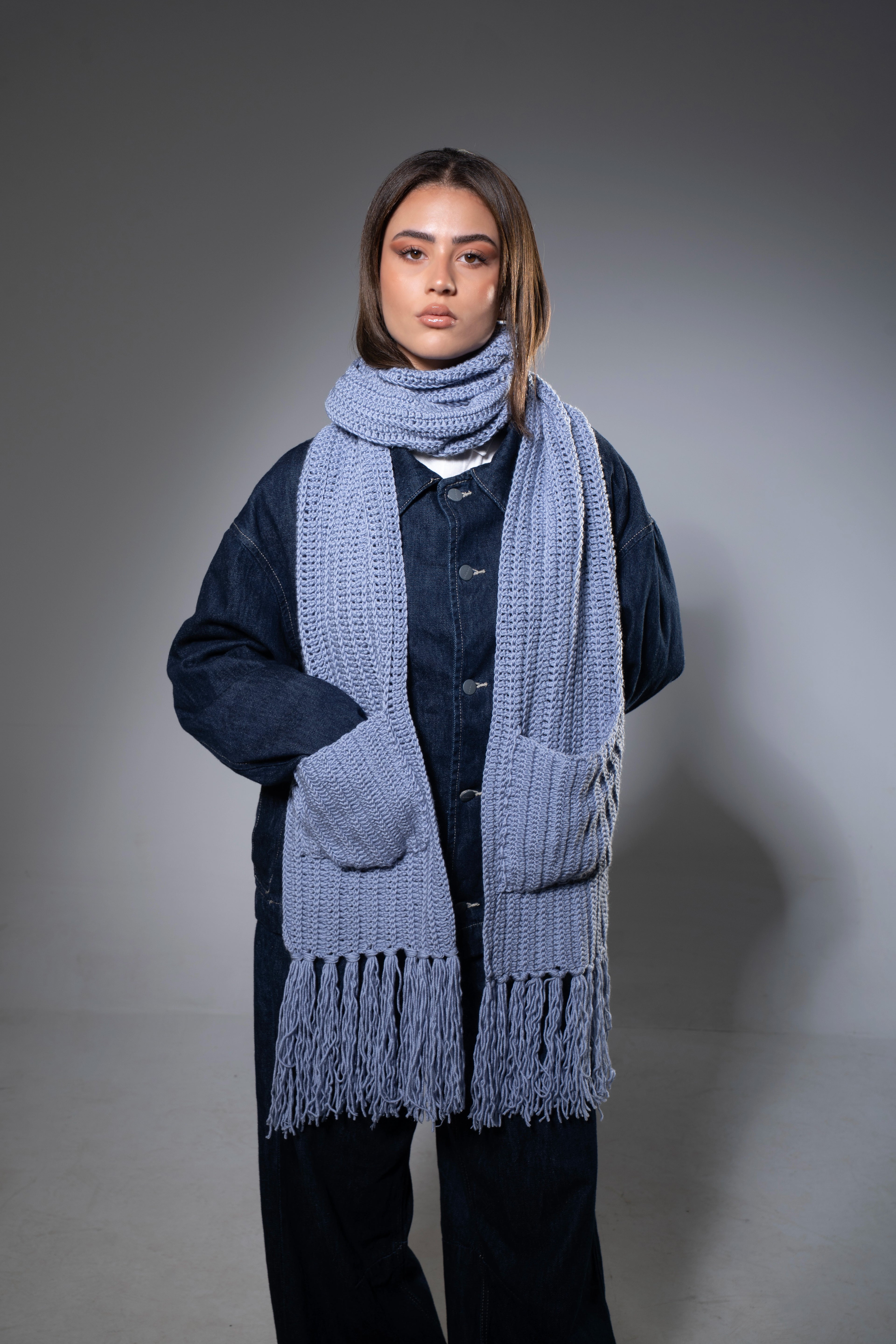 Person wearing a long blue scarf with a gray background