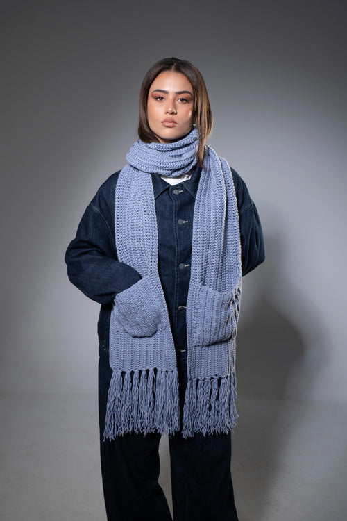 Person wearing a long blue scarf with a gray background