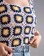 Close-up of a person wearing a colorful crochet top with blue and yellow patterns.