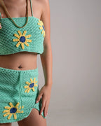 Green crochet top and skirt set with sunflower designs on a neutral background
