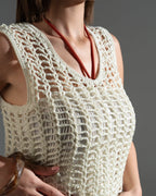 Woman wearing a beige crochet top against a gray background