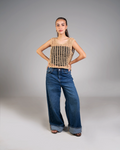 Woman wearing a brown crochet top and blue jeans on a gray background