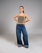 Woman wearing a brown crochet top and blue jeans on a gray background