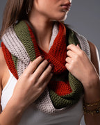 Person wearing a colorful knitted scarf with a neutral background