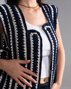 Person wearing a navy and white patterned vest over a white top on a gray background