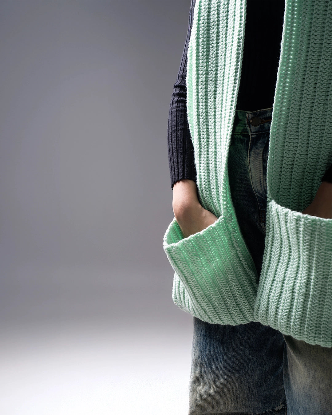 Person wearing a green knitted cardigan with a blurred background