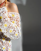 White crochet dress with yellow floral patterns on a gray background