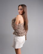 Woman wearing a brown crochet top and white shorts on a gray background