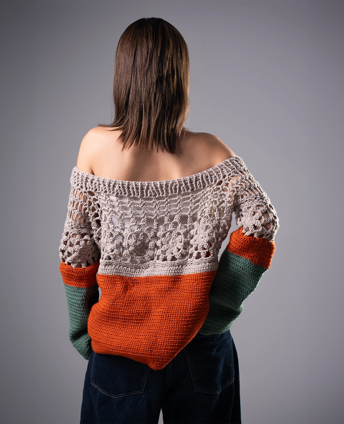 Person wearing a colorful off-shoulder sweater against a gray background