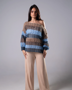 Woman wearing a striped sweater and beige pants against a gray background