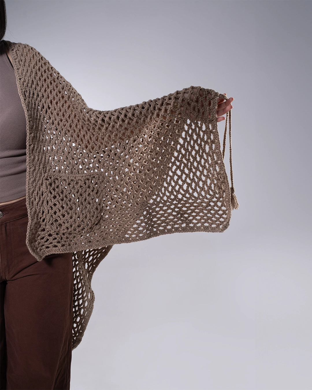 Brown crochet bag held by a person against a plain background