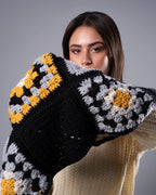 Woman holding a colorful crocheted blanket with a gray background