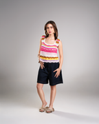 Woman wearing a colorful sleeveless top and black shorts on a gray background
