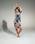 Woman wearing a colorful crochet dress against a plain background