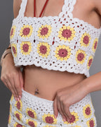 Woman wearing a white dress with floral embellishments on a gray background