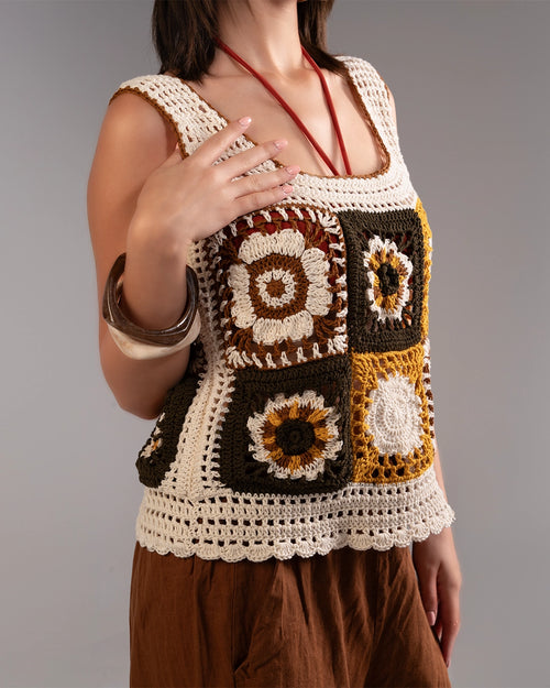 Person wearing a crocheted square-patterned top with brown and beige colors on a gray background