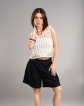 Woman wearing a white crochet top and black shorts on a gray background