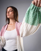 Woman wearing a colorful crocheted cardigan against a gray background