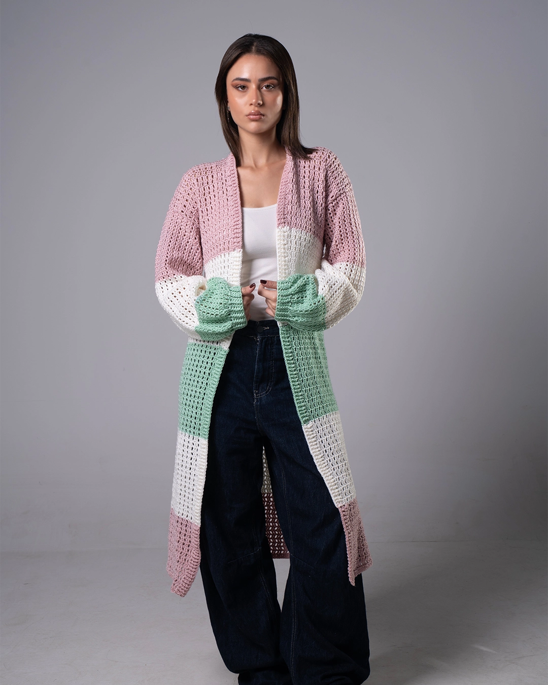 Woman wearing a colorful crocheted cardigan on a gray background