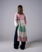 Person wearing a long, colorful cardigan with a striped pattern on a plain background