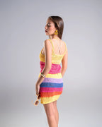 Woman wearing a colorful crochet dress on a gray background